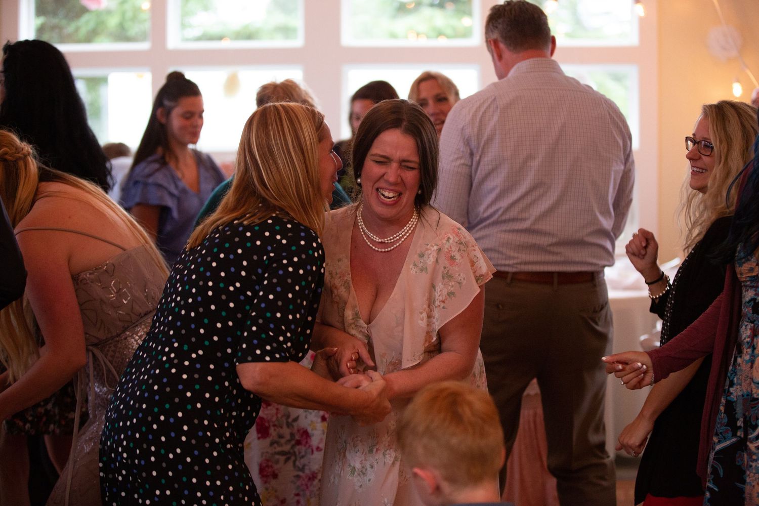 Guests laughing and dancing together during lively wedding reception celebration.