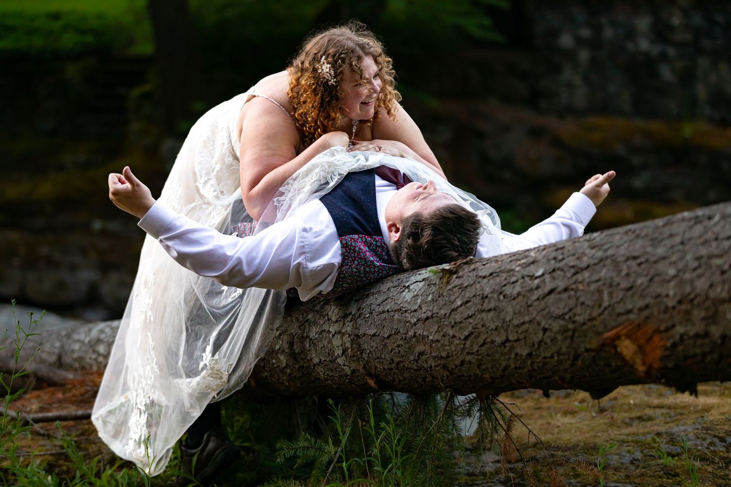 A romantic photoshoot set against a natural woodland backdrop with fallen trees.