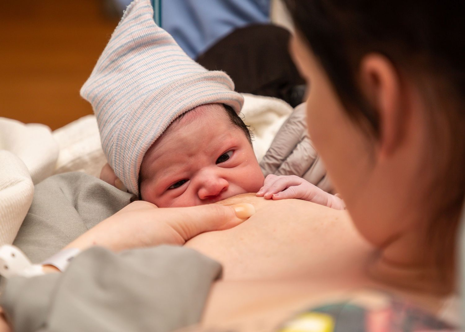 Newborn baby wrapped in white blanket being held by medical professional in blue scrubs.