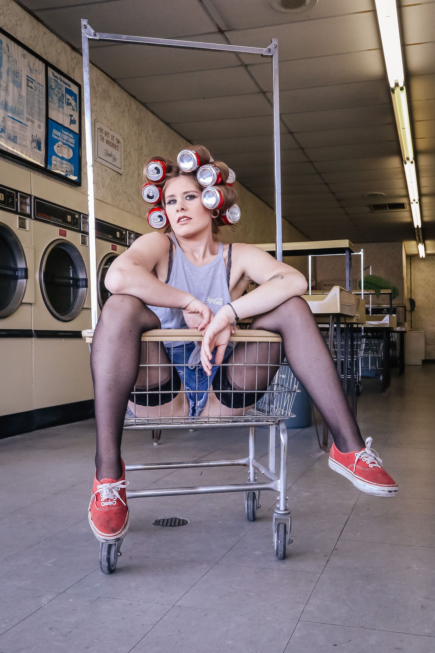 Vintage laundromat interior with metal shopping cart and rows of washing machines.