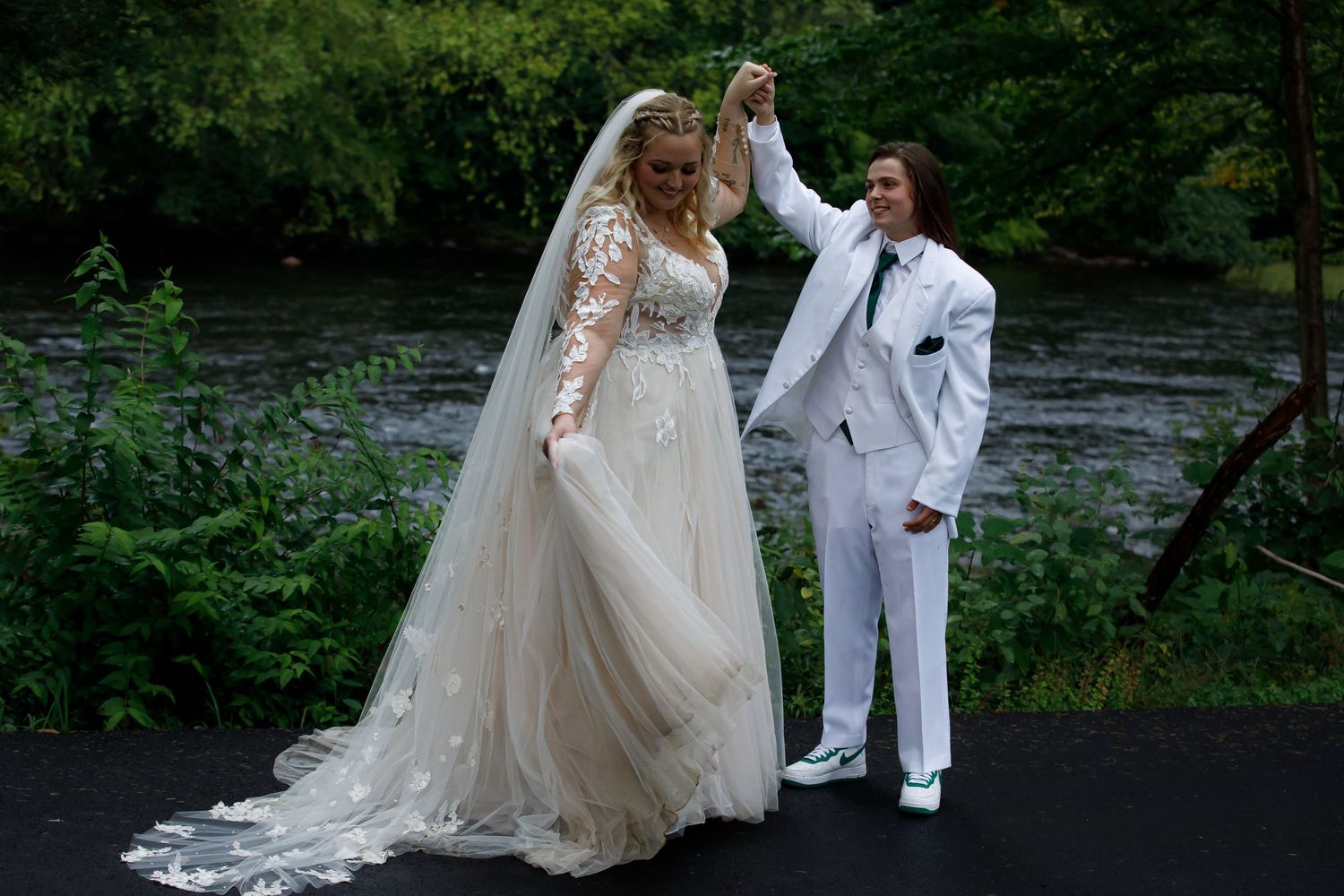 Couple sharing a romantic dance moment by a river in wedding attire.