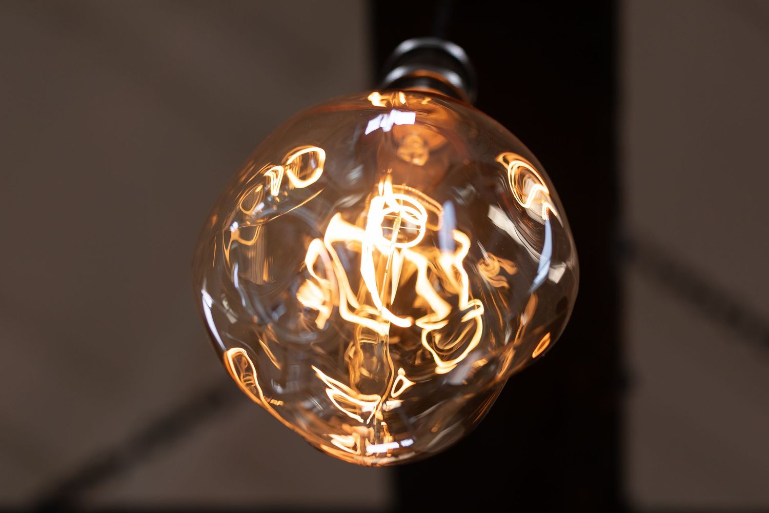 Close-up sequence of vintage Edison light bulbs glowing with warm filaments against dark background.