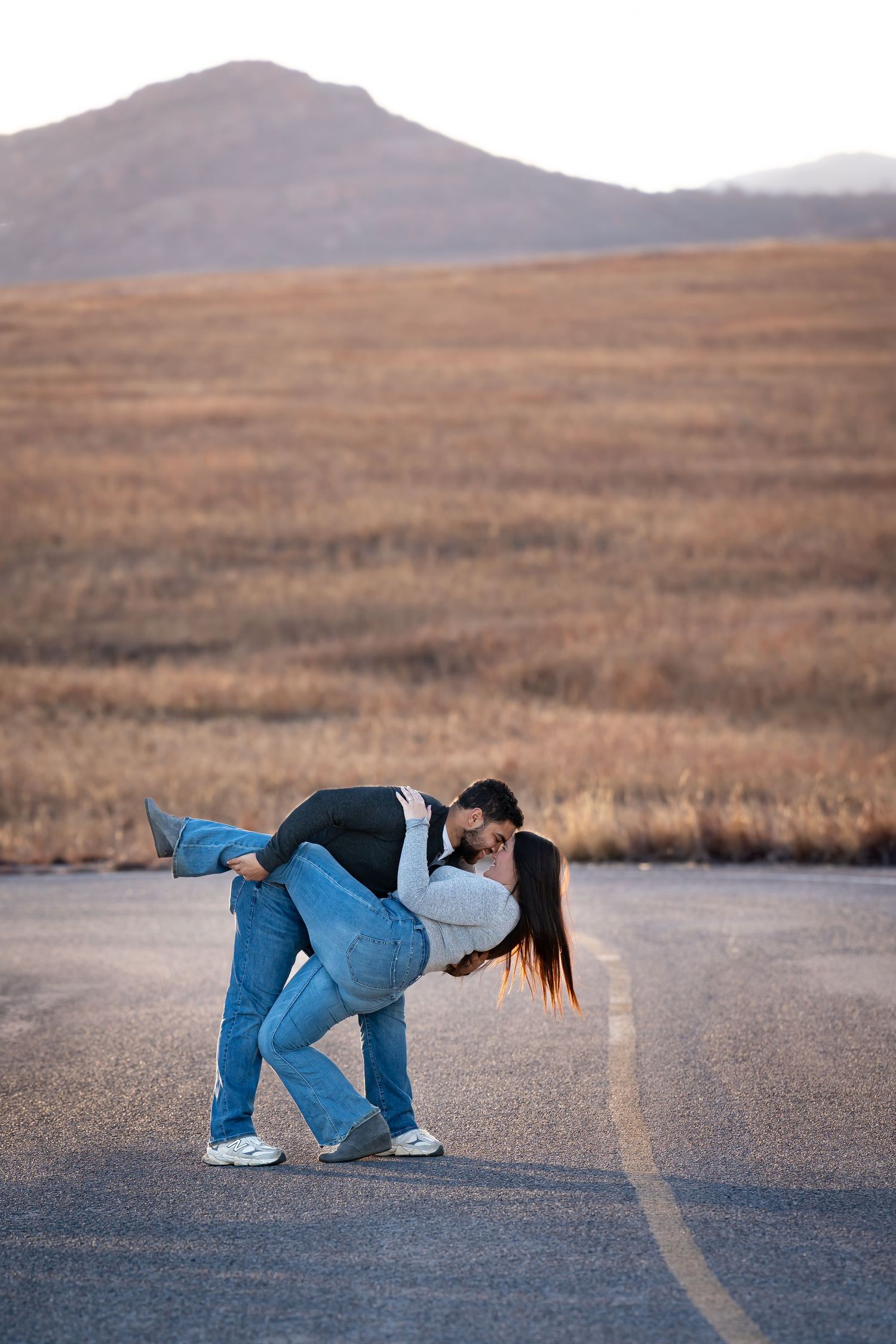A sequence of photos shows someone in blue jeans doing a backbend on an empty road with desert mountains in the background.