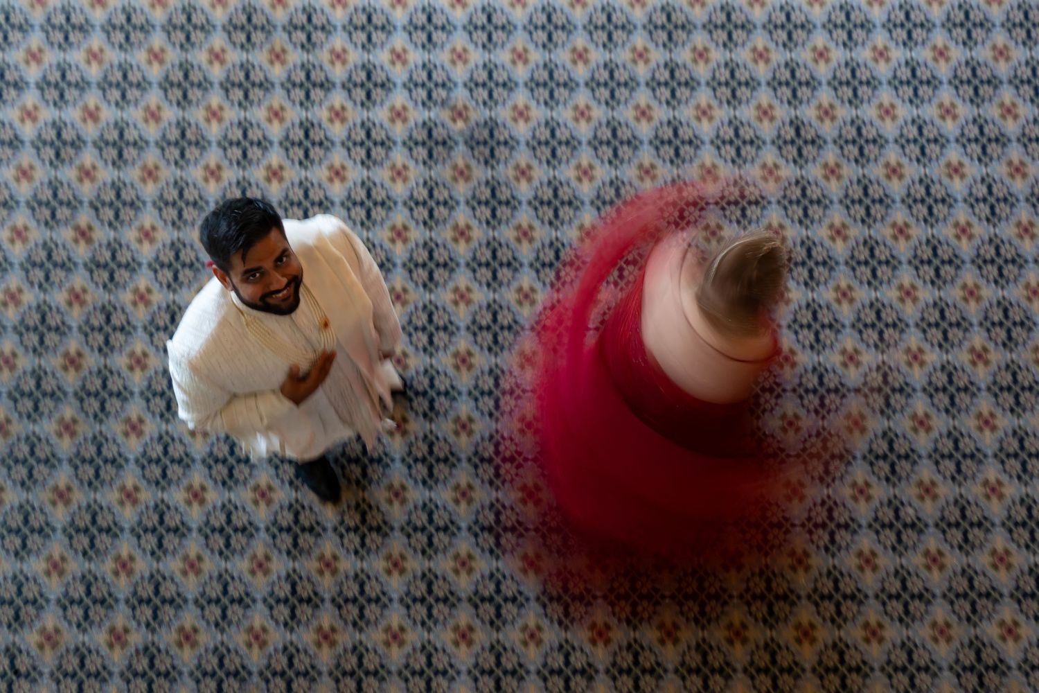 Overhead view of couples dancing on a patterned ballroom floor.