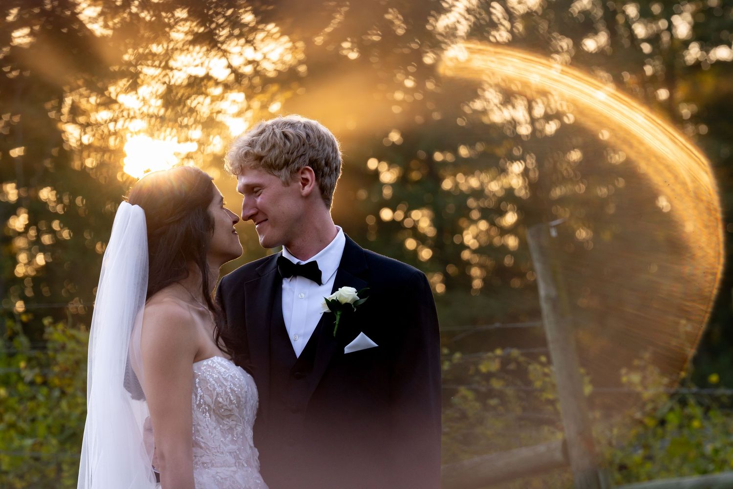 Romantic sunset wedding portrait with dramatic veil movement and golden light.