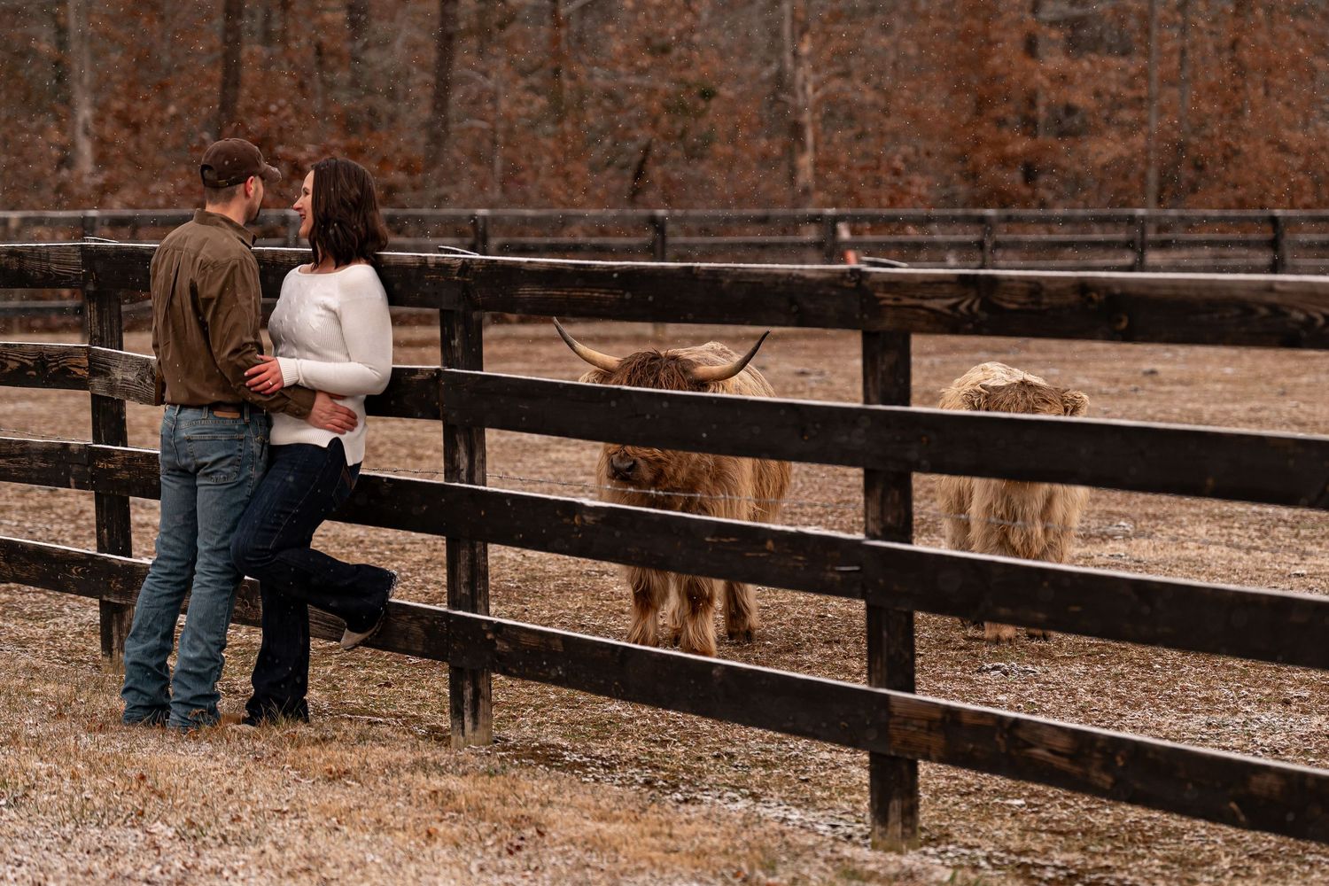 Wooden fence stretches along rustic outdoor setting during engagement photo shoot.