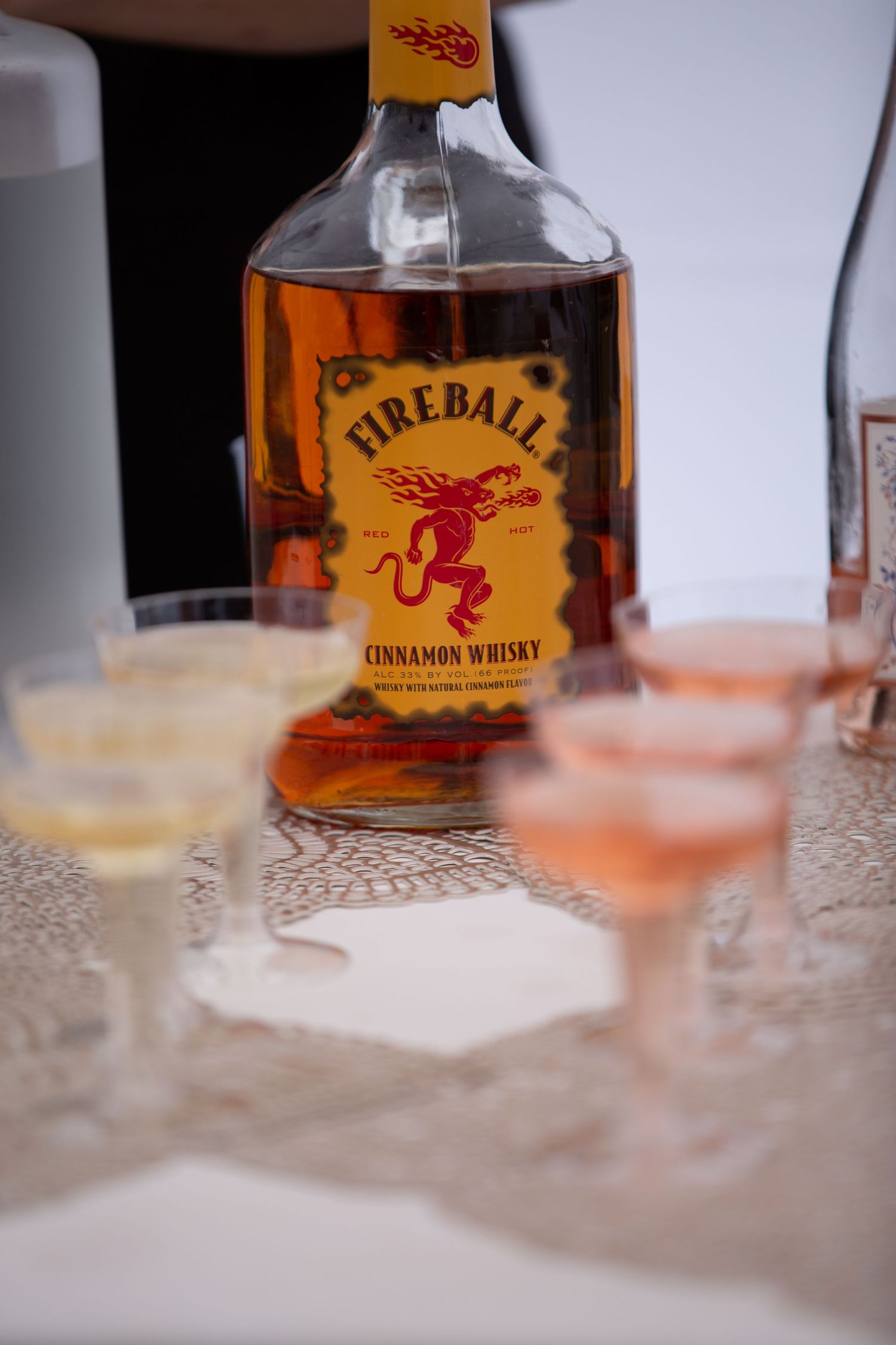 Fireball cinnamon whiskey bottles arranged with cocktail glasses on a textured surface.