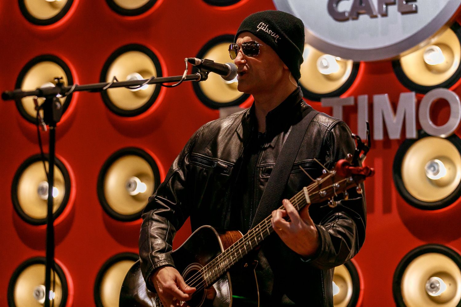 Acoustic guitar performance at Hard Rock Cafe with dramatic red lighting and circular wall decorations.