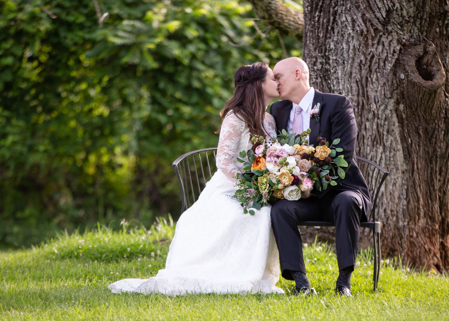 Romantic wedding portraits under large tree in summer garden.