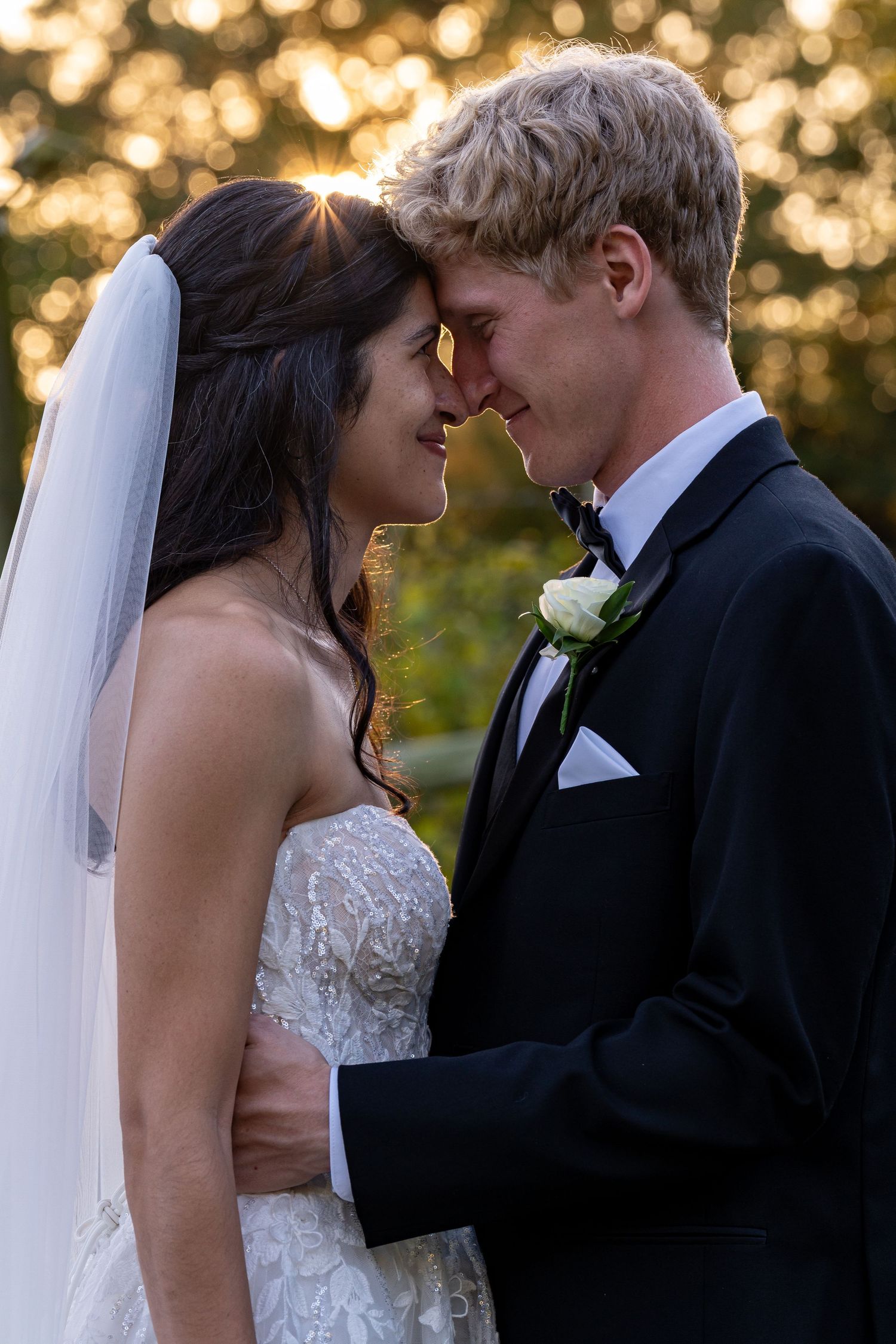Intimate wedding portrait with golden sunset bokeh lighting in the background.