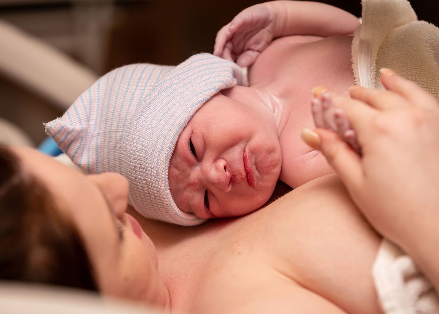 Newborn baby receiving initial care and examination in hospital delivery room.