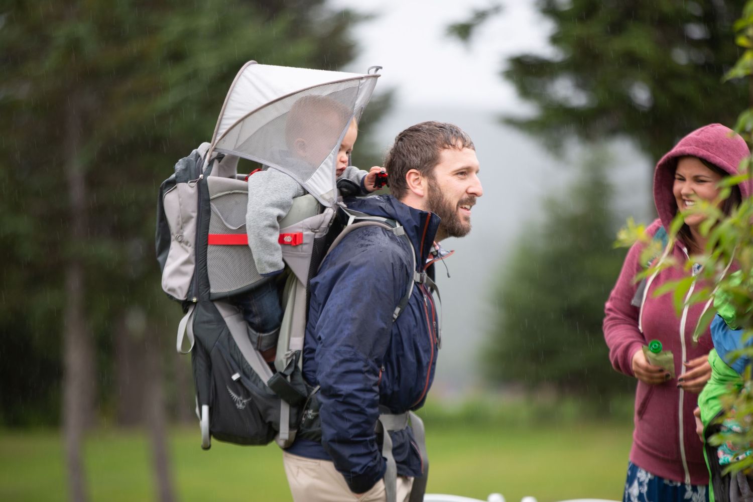 Wedding guests walking outdoors on a rainy day carrying umbrellas.