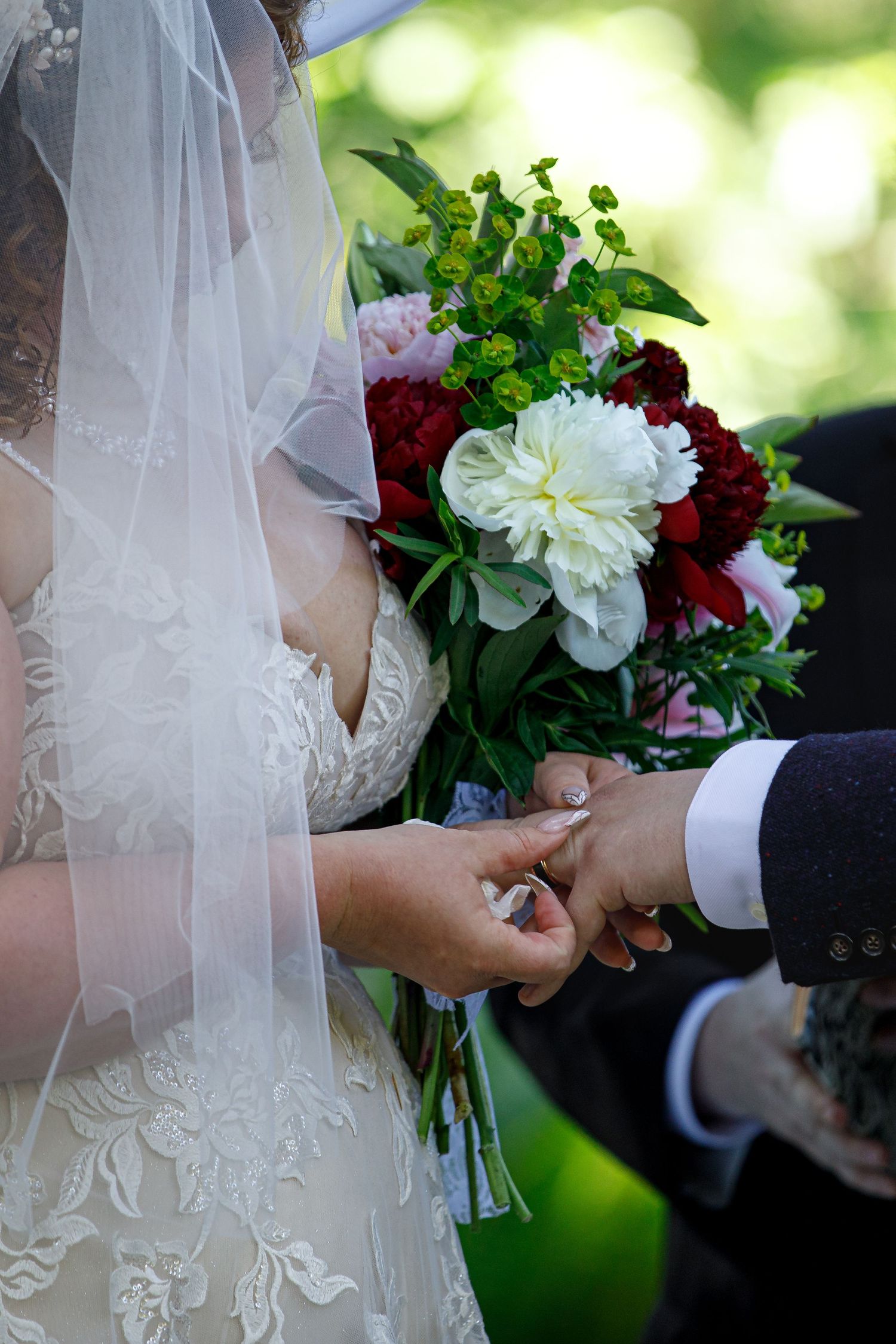Close-up of wedding bouquet with white and burgundy flowers during ceremony.