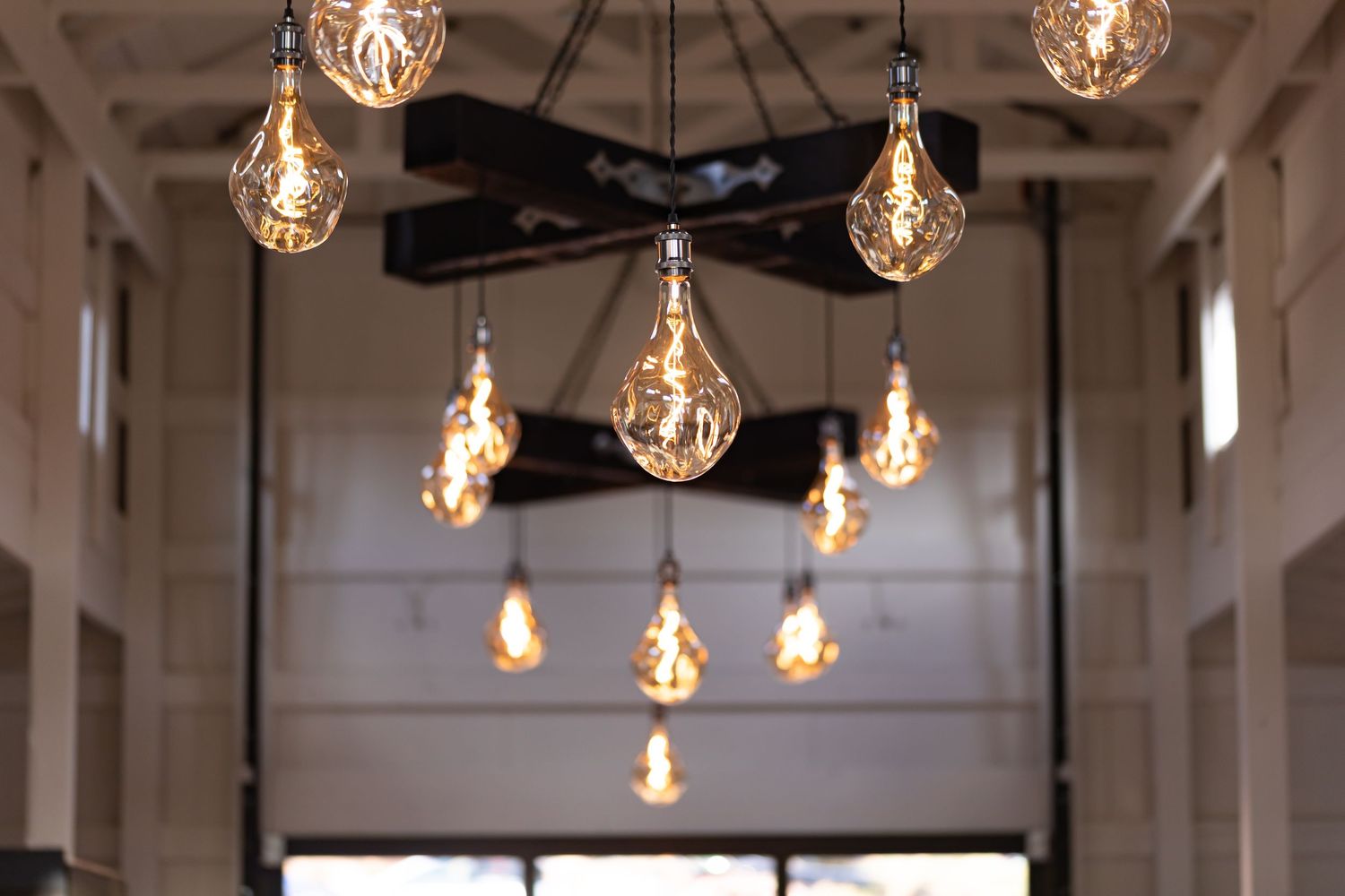 Modern pendant lights arranged in artistic pattern inside industrial-style venue.
