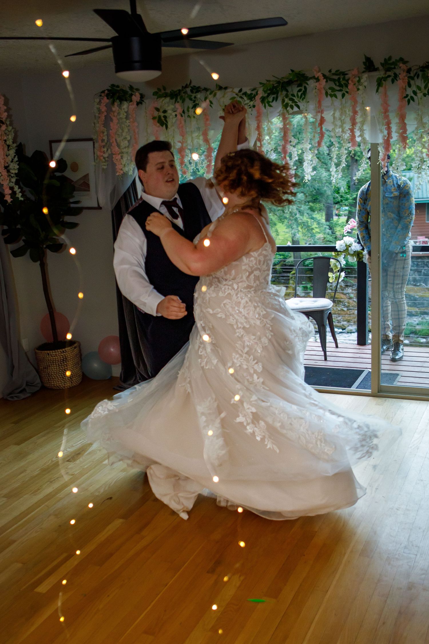 A dancing couple twirls across a wooden floor during their wedding reception.