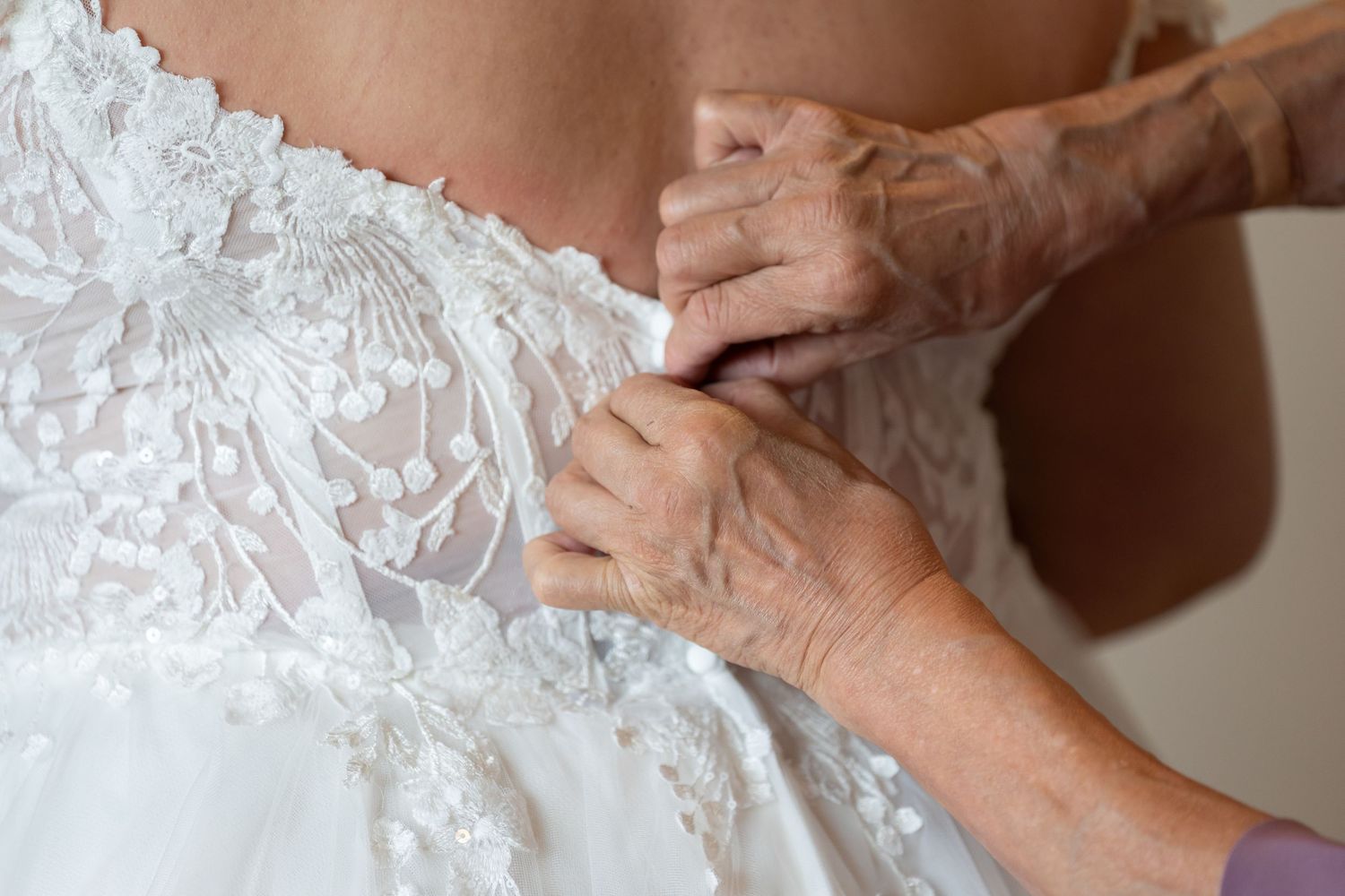 Close-up of intricate lace details on a white wedding dress bodice.