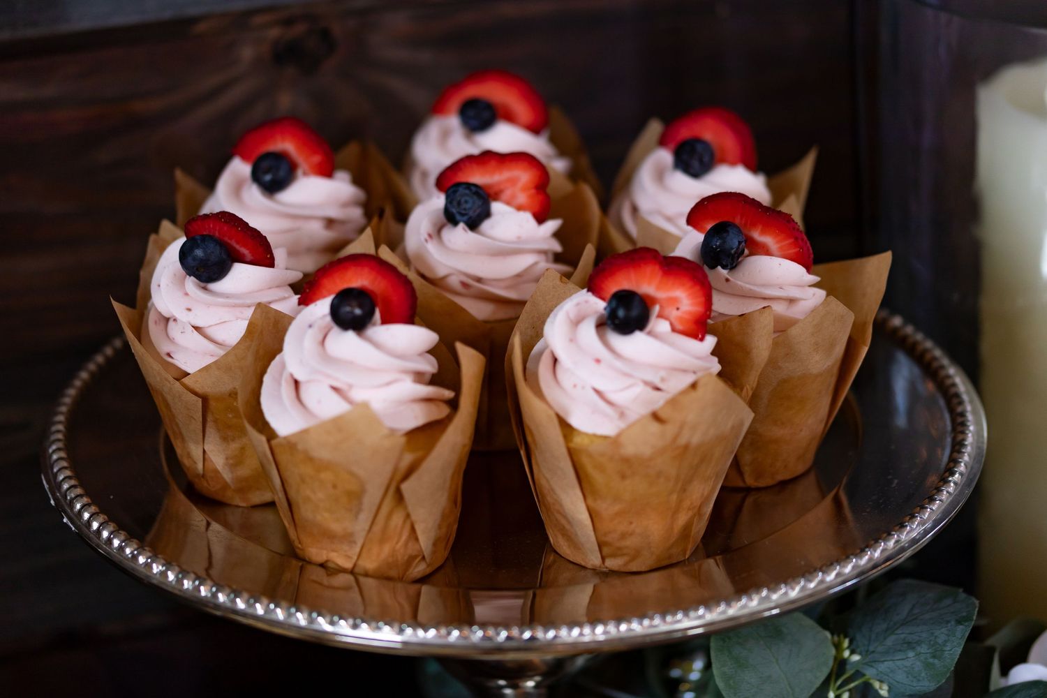 Red and white decorated cupcakes arranged on a silver serving platter.