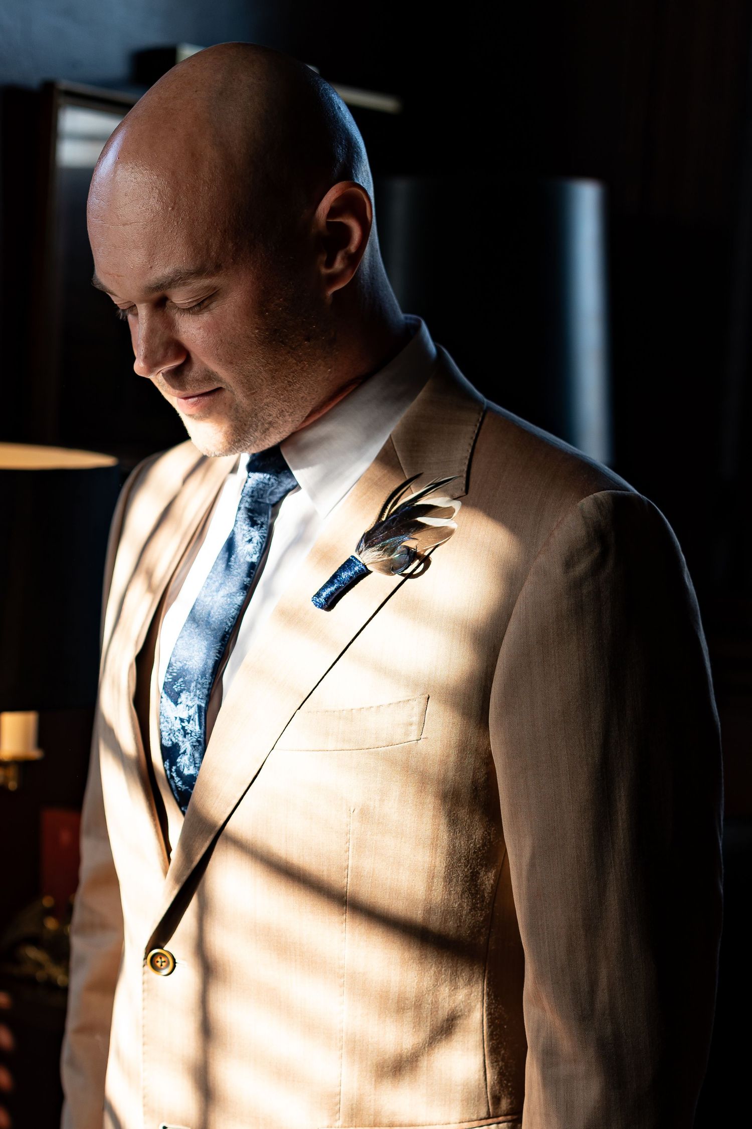Dramatic lighting highlights a tan suit jacket and blue tie in a series of photos.