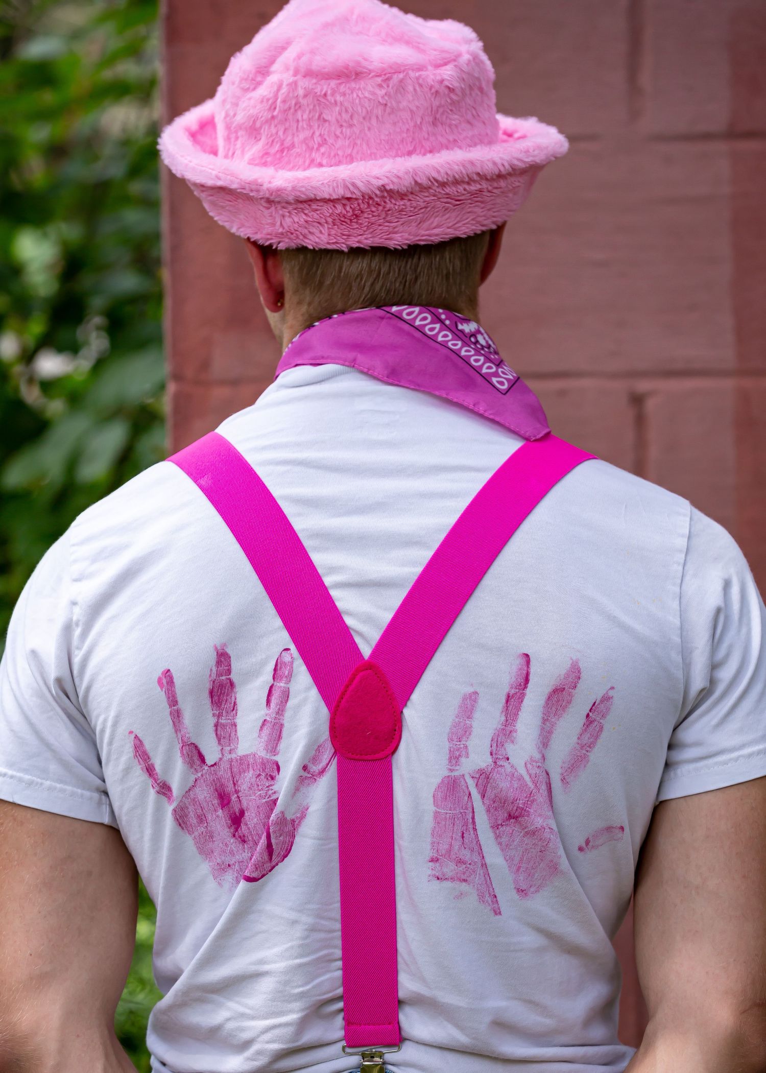 Back view of white shirt with pink handprints and suspenders.