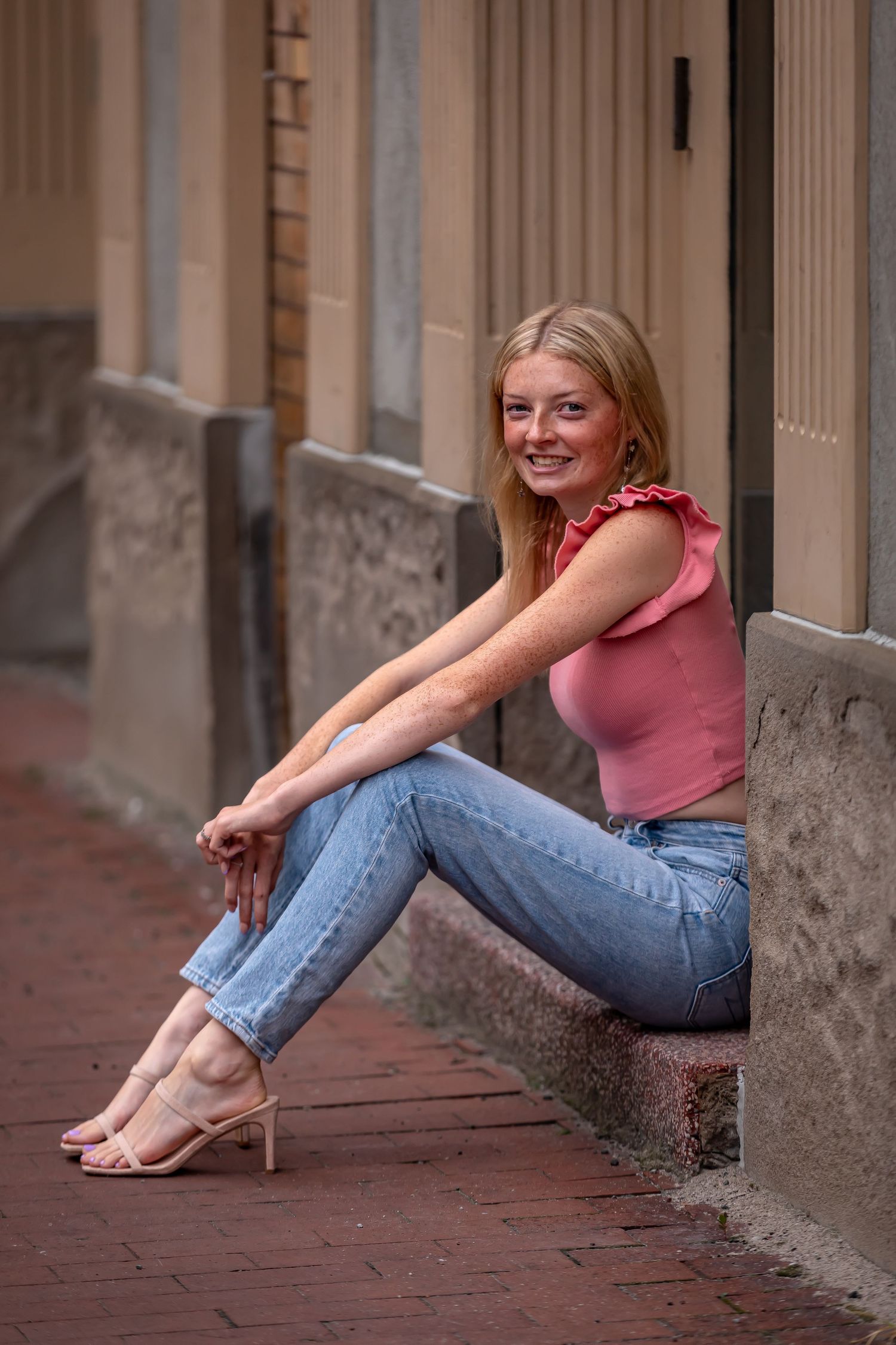 Casual portrait session on red brick sidewalk with architectural details.