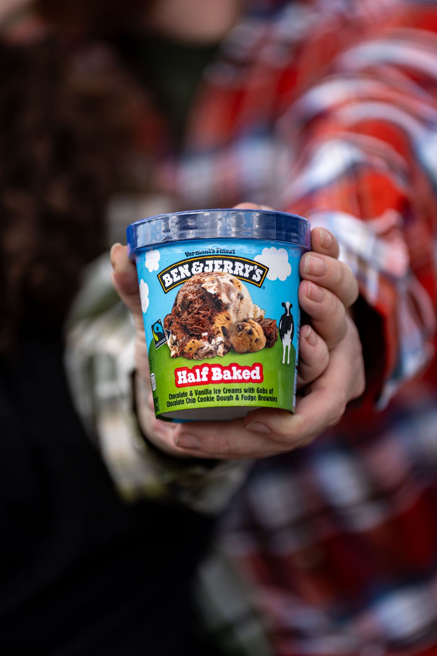 Ben & Jerry's Half Baked ice cream pint being held against a blurred background.