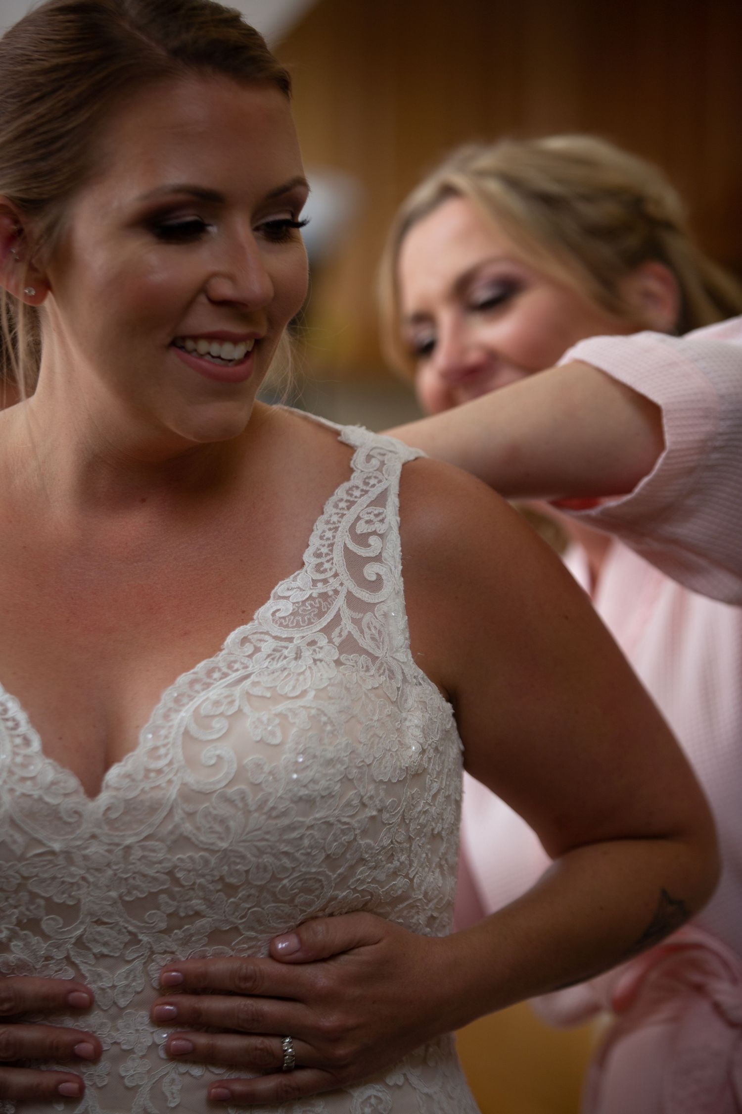 Close up details of a white lace wedding dress being adjusted.