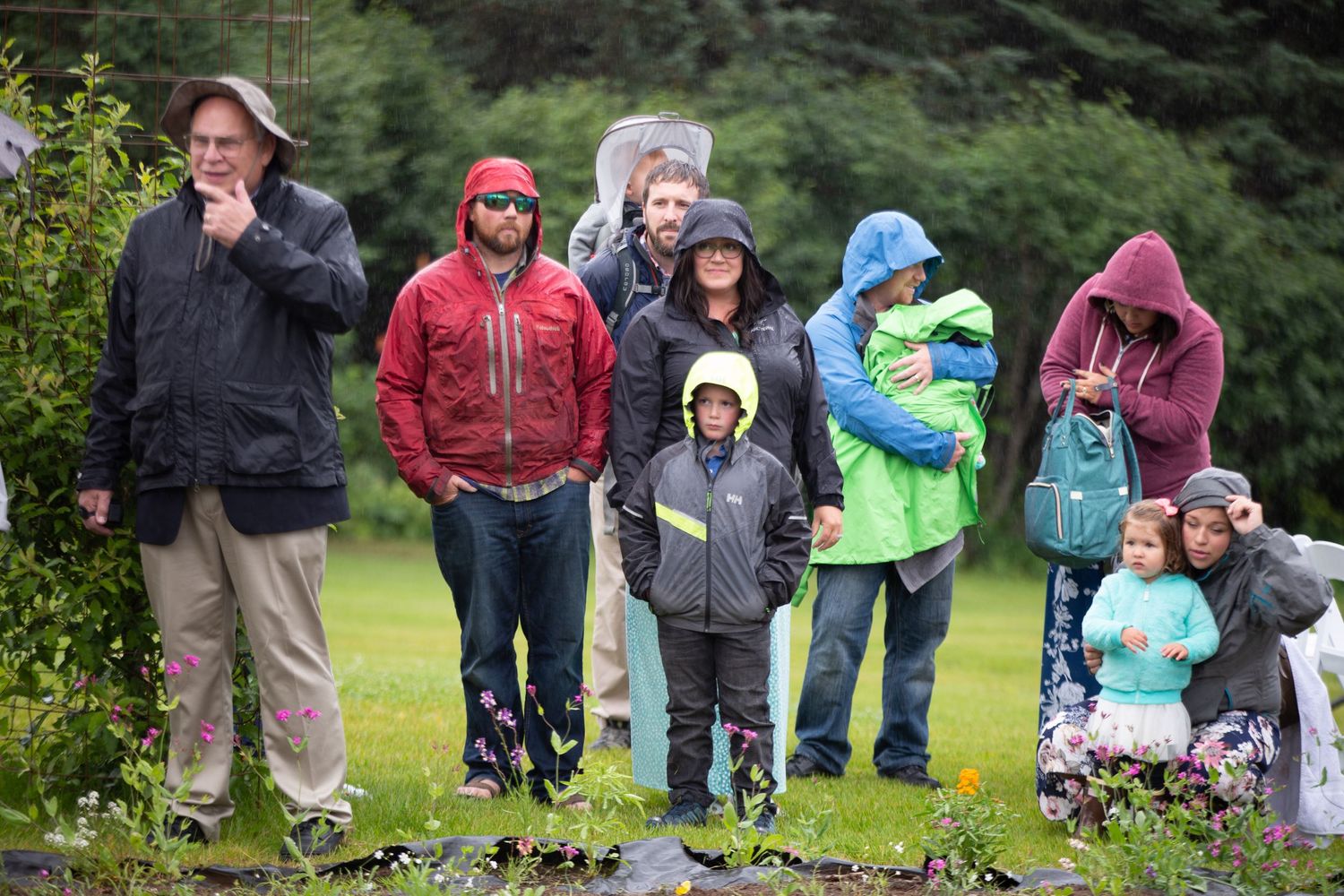 Group of people walking along a rainy outdoor path wearing rain gear and jackets.