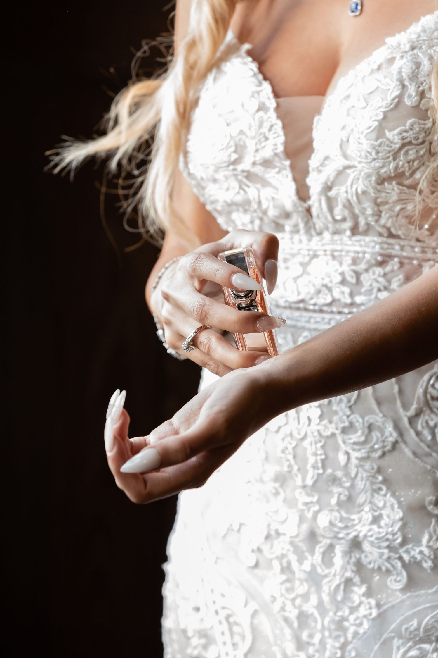 Close-up details of perfume bottle and lace wedding dress bodice.