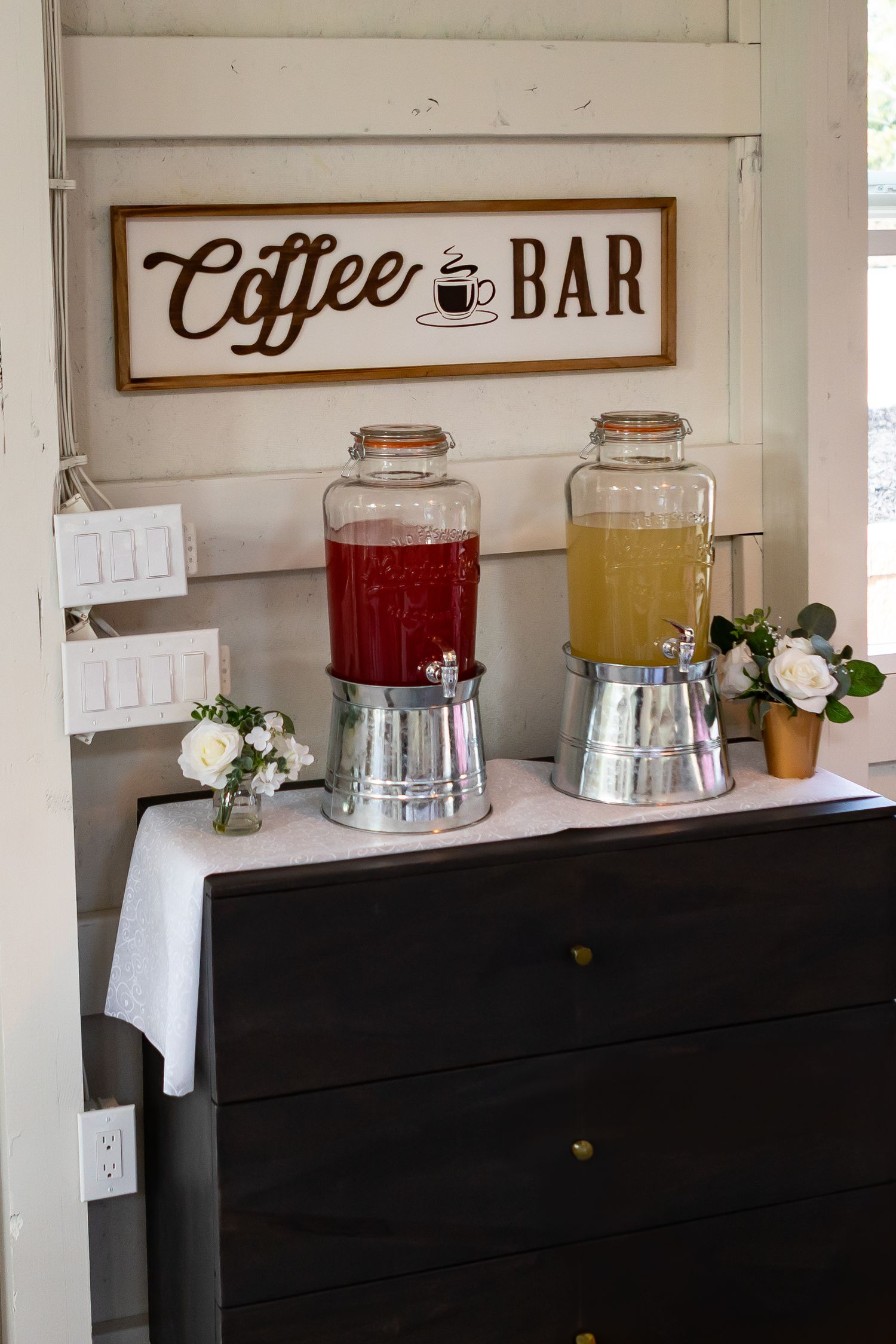 Coffee bar station with white cabinetry and beverage dispensers displaying drink options.