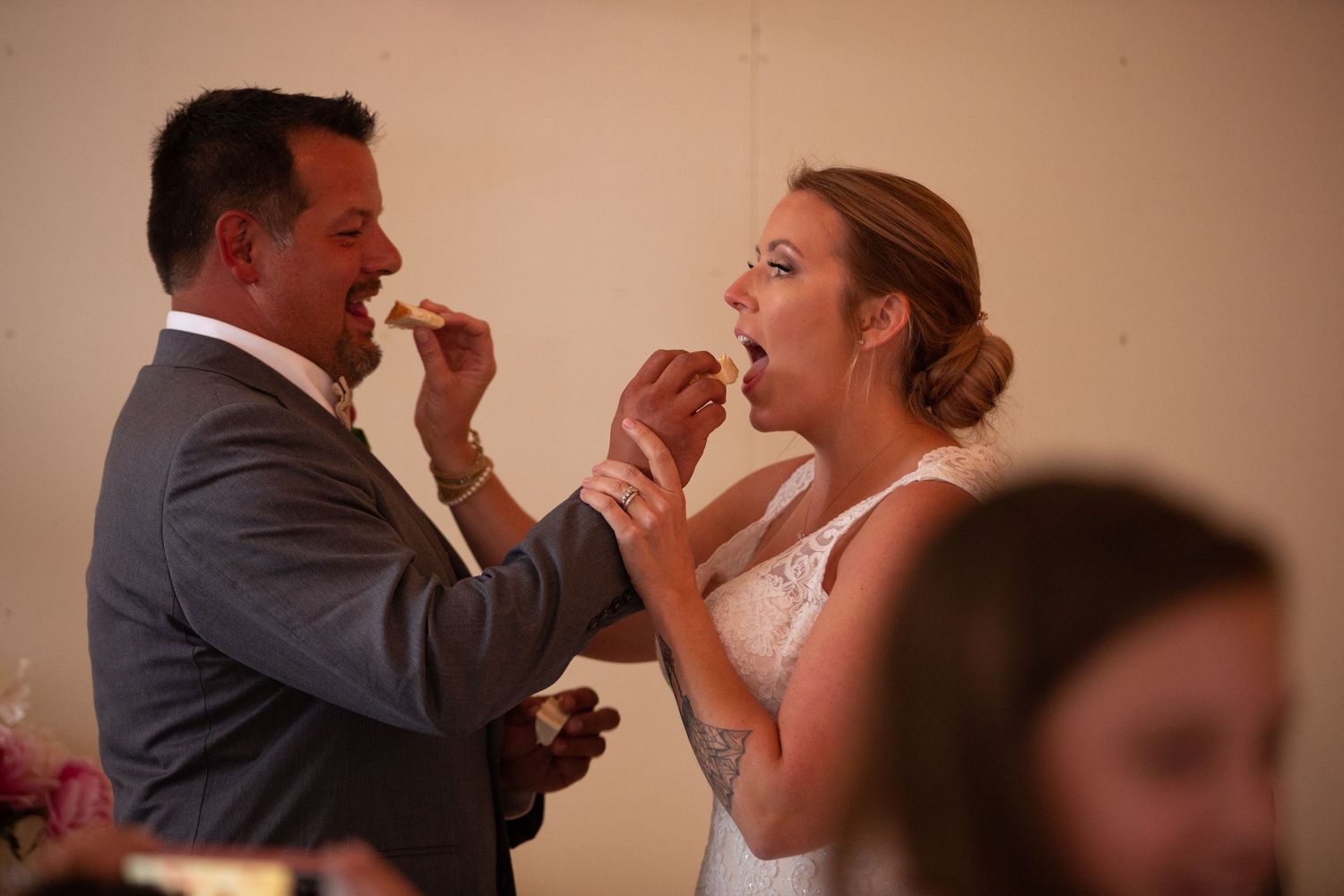 Couple feeding each other cake during traditional wedding reception moment.