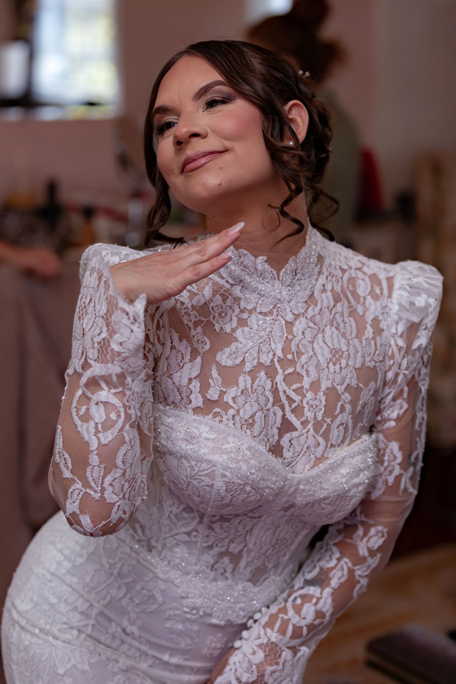 Bride in elegant lace long sleeve wedding dress posing indoors.
