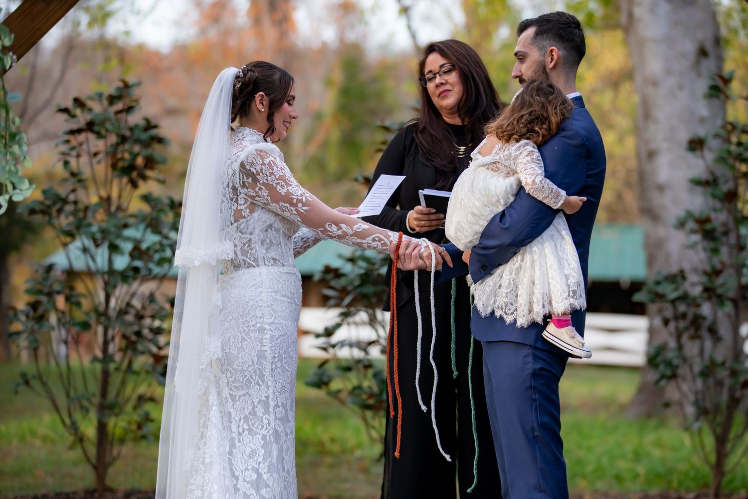Outdoor wedding ceremony with couple and officiant in natural setting.