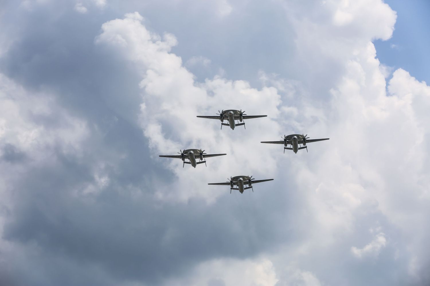 Military aircraft flying in formation against cloudy sky during homecoming ceremony.