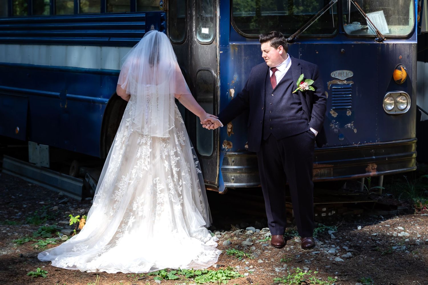 An outdoor wedding photoshoot featuring a bride and groom with a vintage blue bus as backdrop.