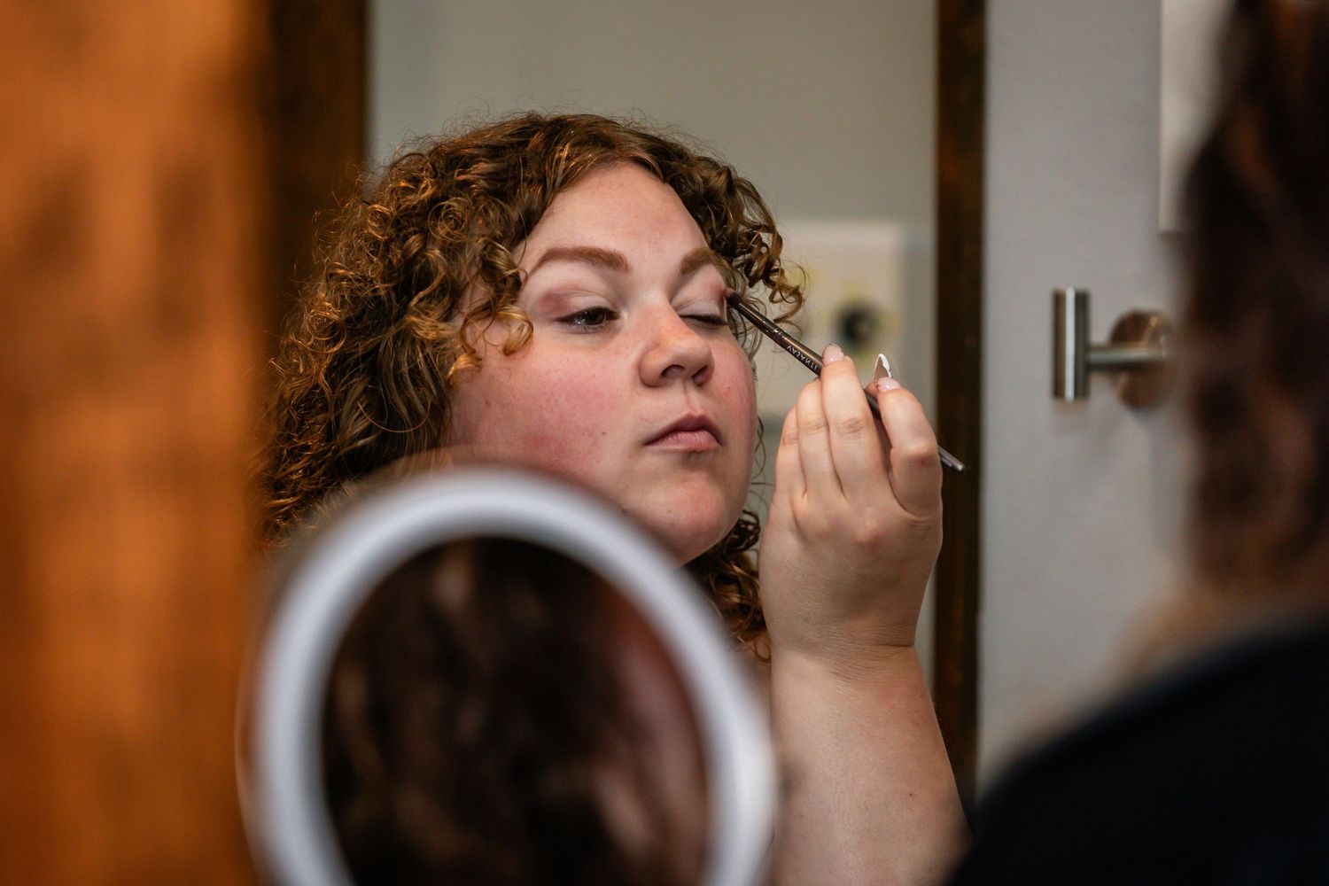 Close up of someone with curly hair getting their makeup done.