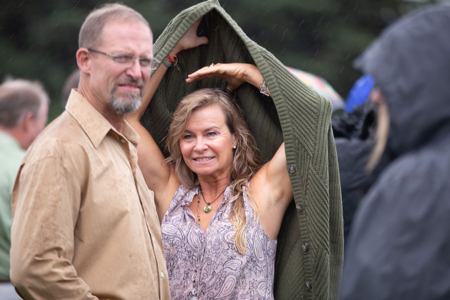 A couple shares a romantic moment during an outdoor wedding celebration against a natural backdrop.