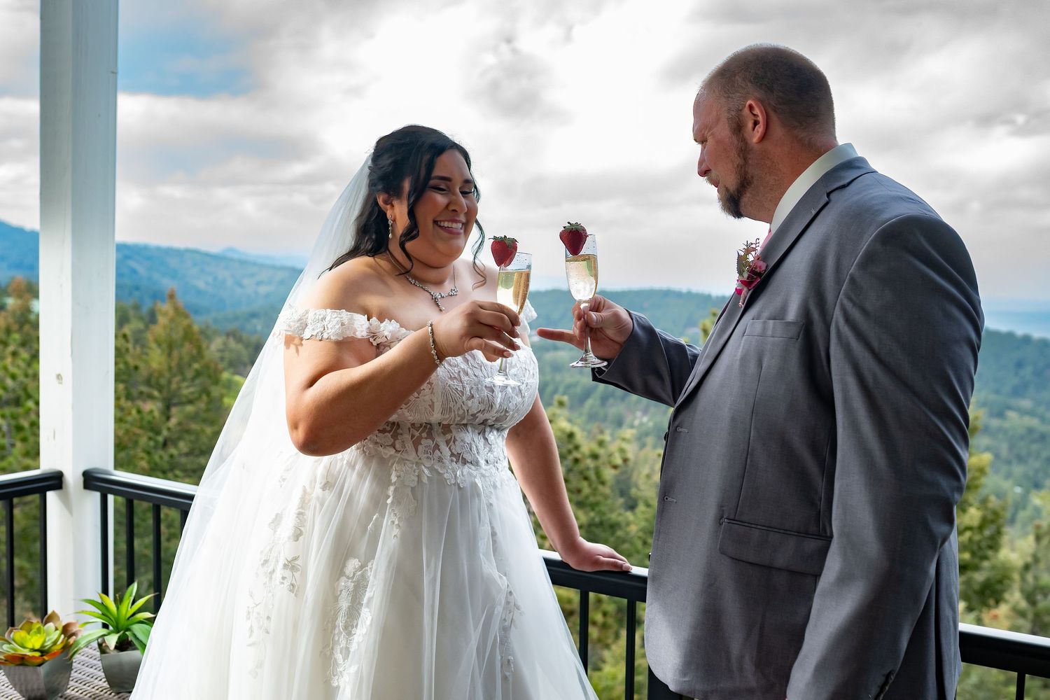 Couple sharing wine toast on mountain view balcony.