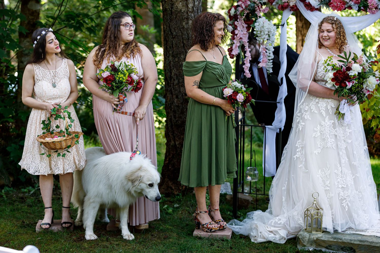 Wedding party members standing in a line outdoors with bridesmaids in sage green dresses.