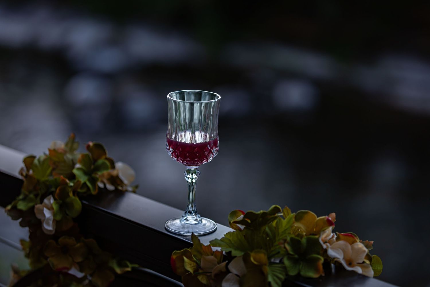 Wine glasses illuminated in dark atmospheric lighting at an evening event.