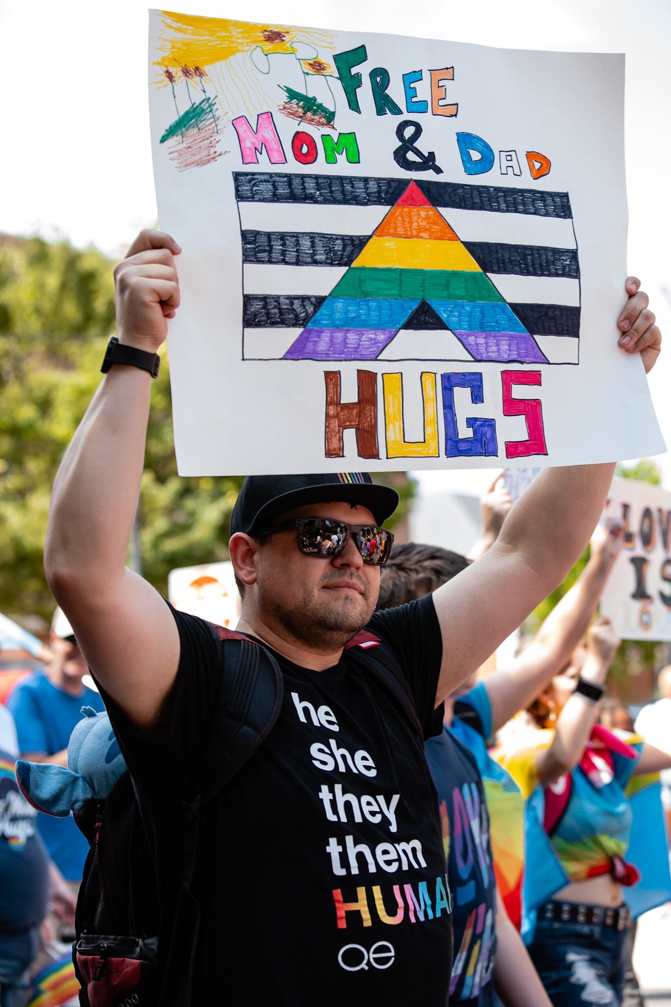 Pride festival attendee holding rainbow colored signs with supportive messages.