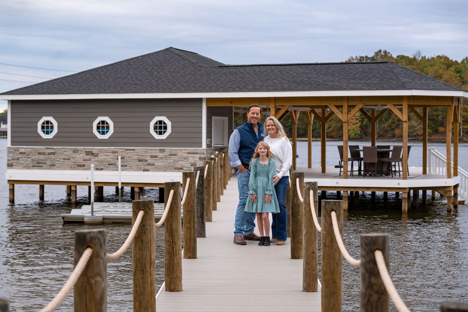Wedding couple on wooden pier overlooking calm waters and distant shoreline.