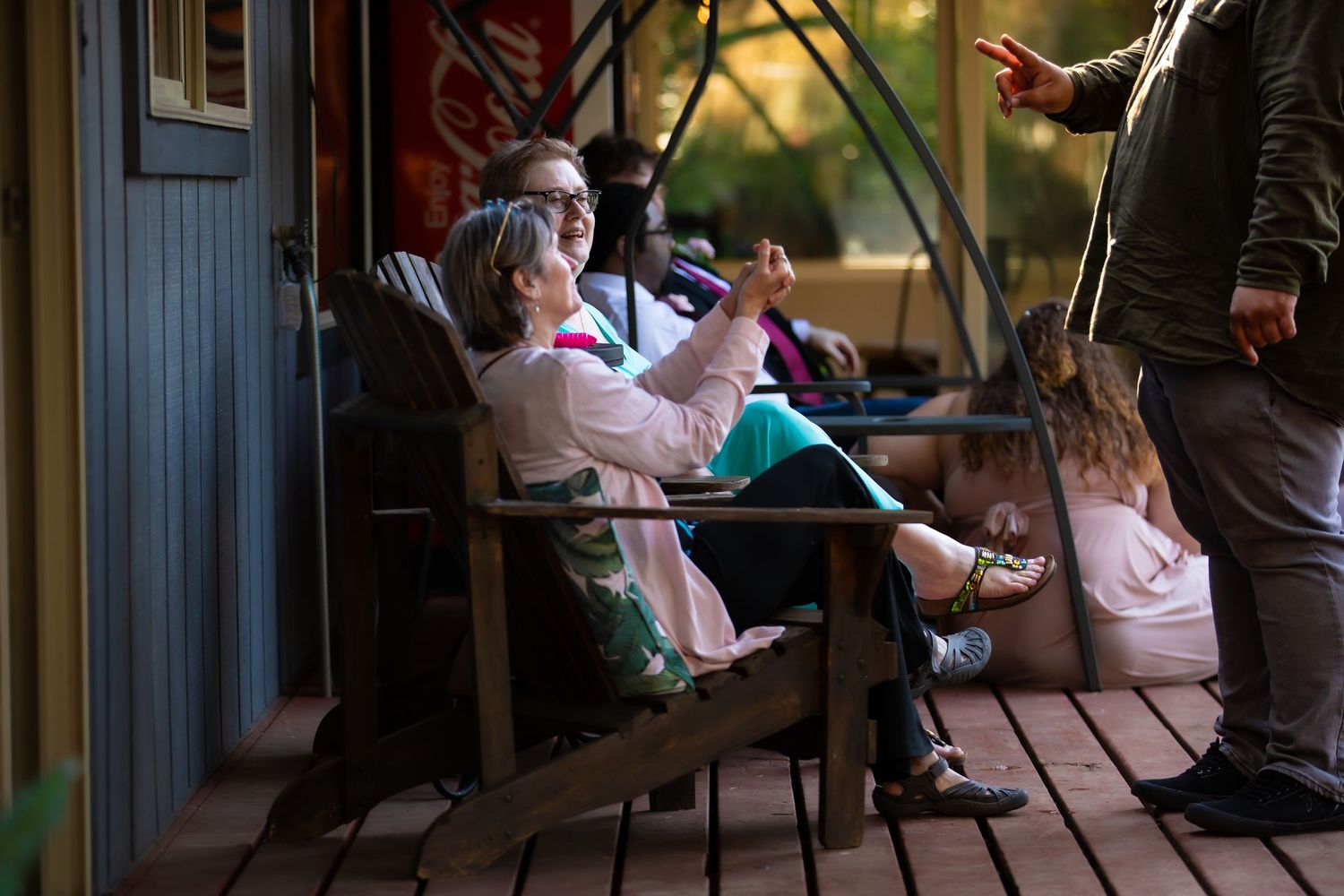 Wedding reception guests enjoy a casual outdoor gathering on a deck.