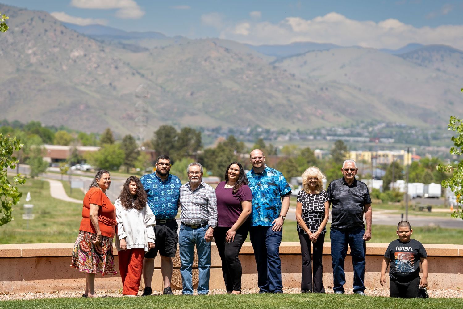 A group photo taken outdoors with mountains and urban landscape in the background.
