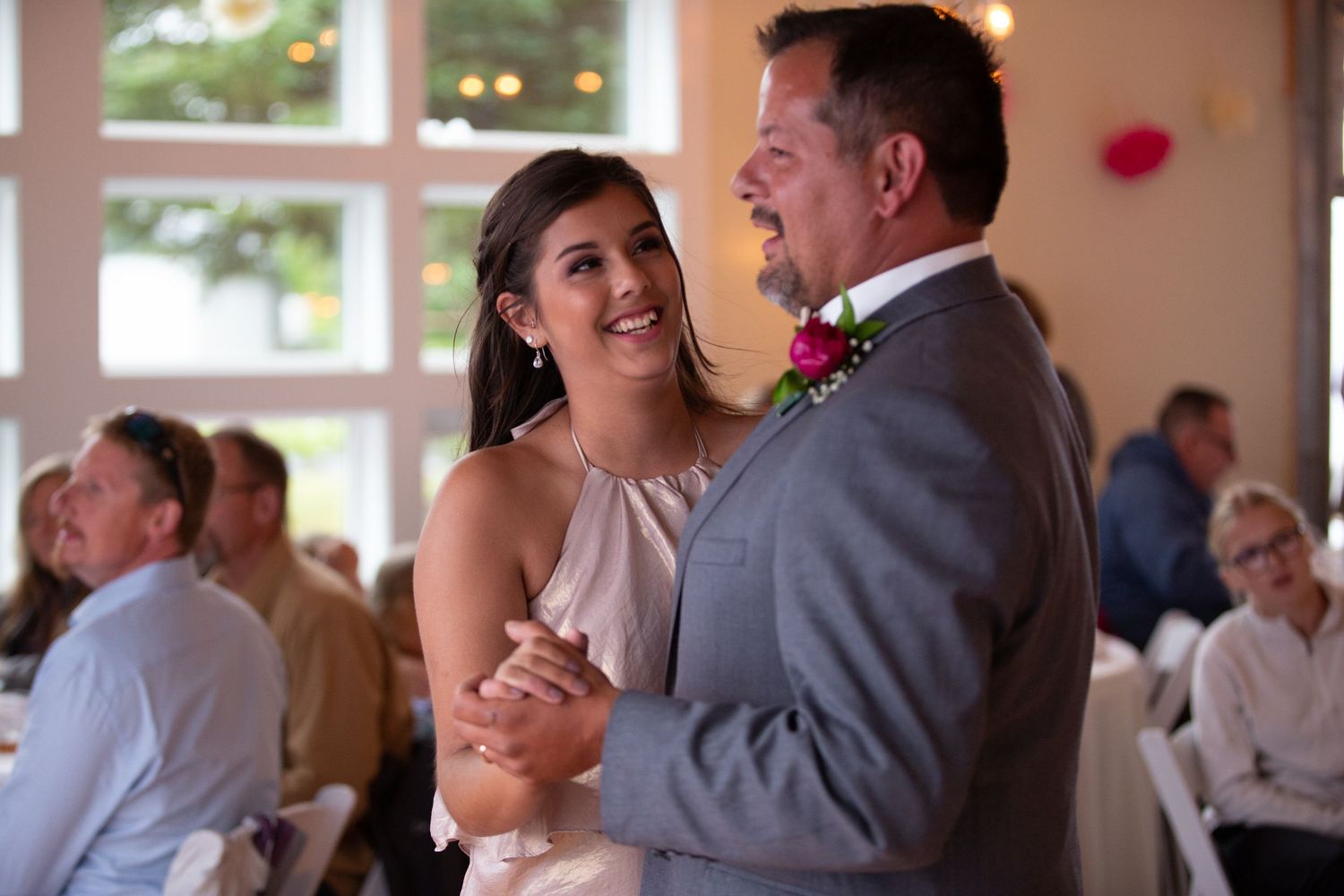 A joyful couple dances and laughs together during their first dance at a wedding reception.