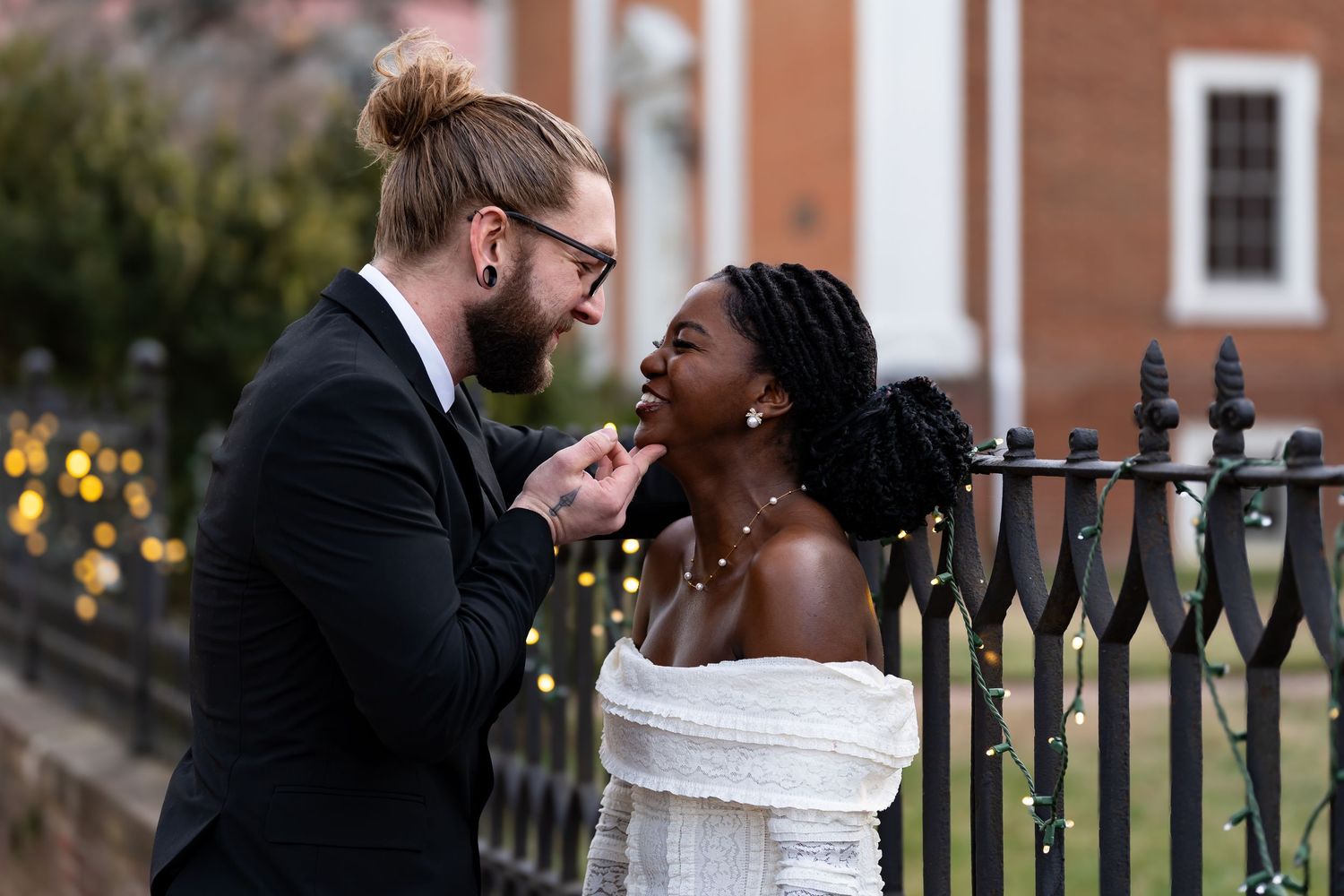 A romantic moment shared between a couple by an ornate iron fence.