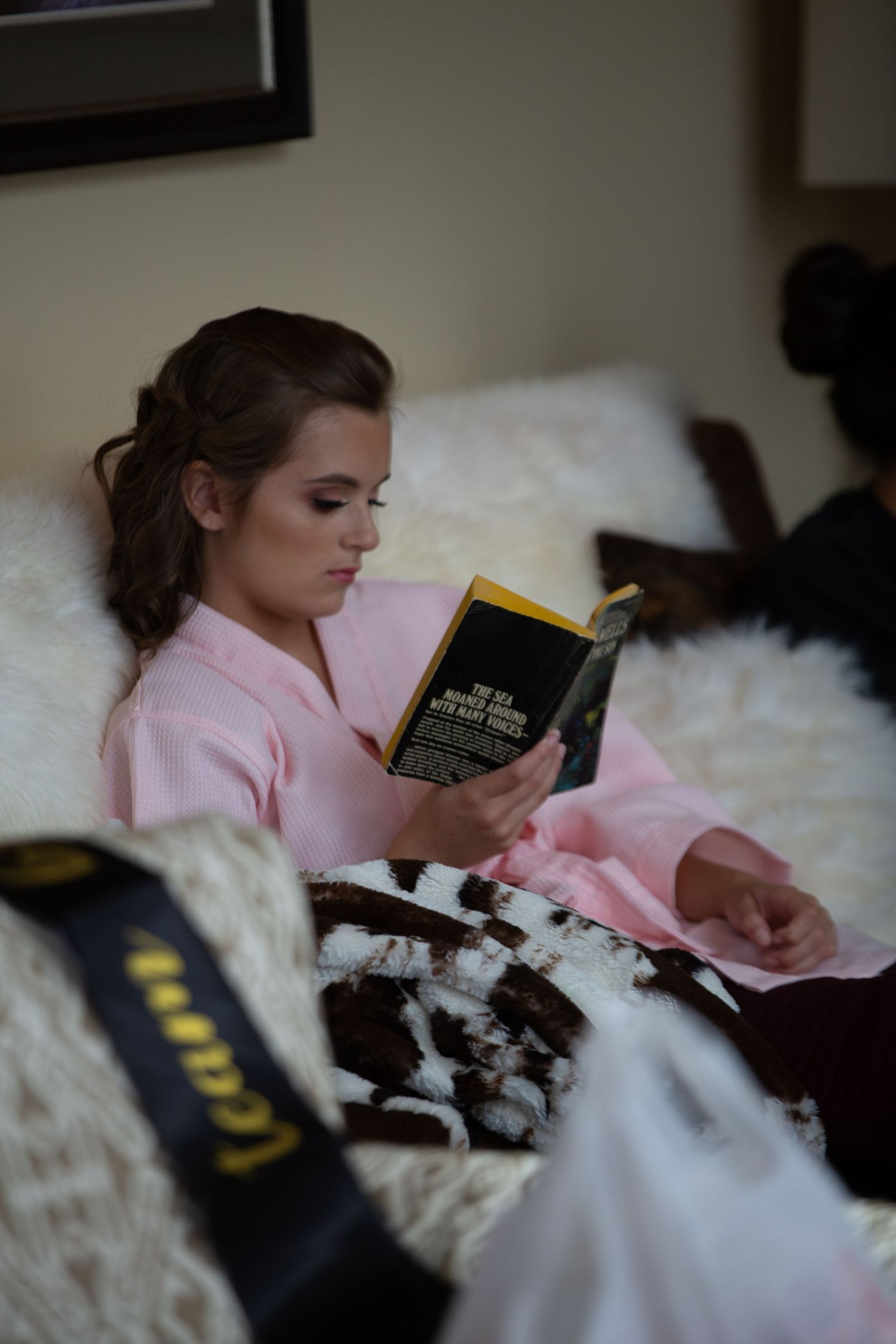 A cozy reading moment in bed with a dog nestled among white blankets.