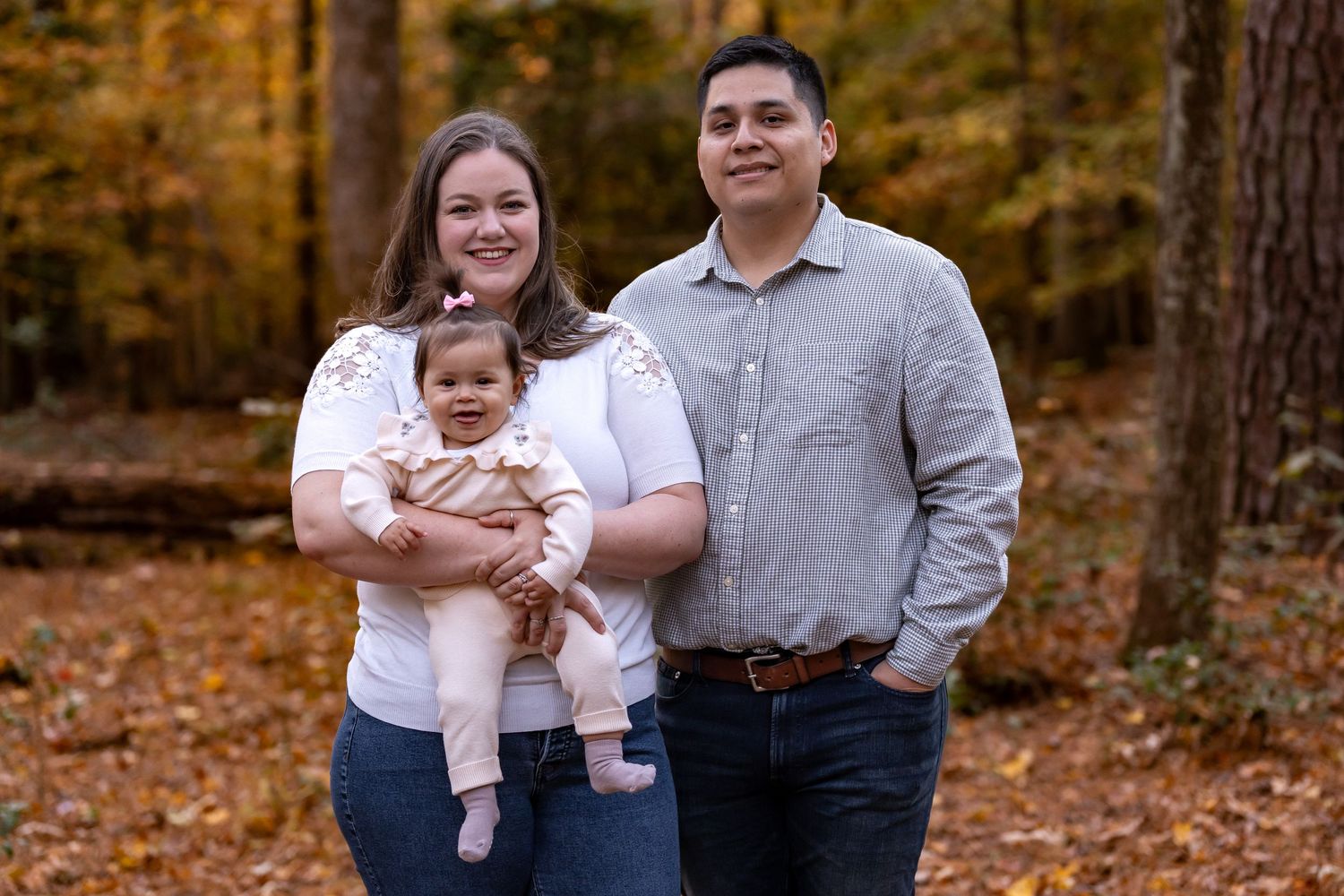 A family poses together in a wooded area during autumn.