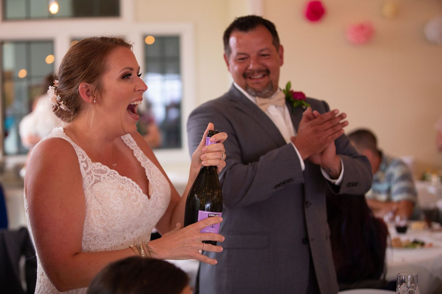 Wedding reception guests enjoying drinks and conversation in decorated indoor venue.