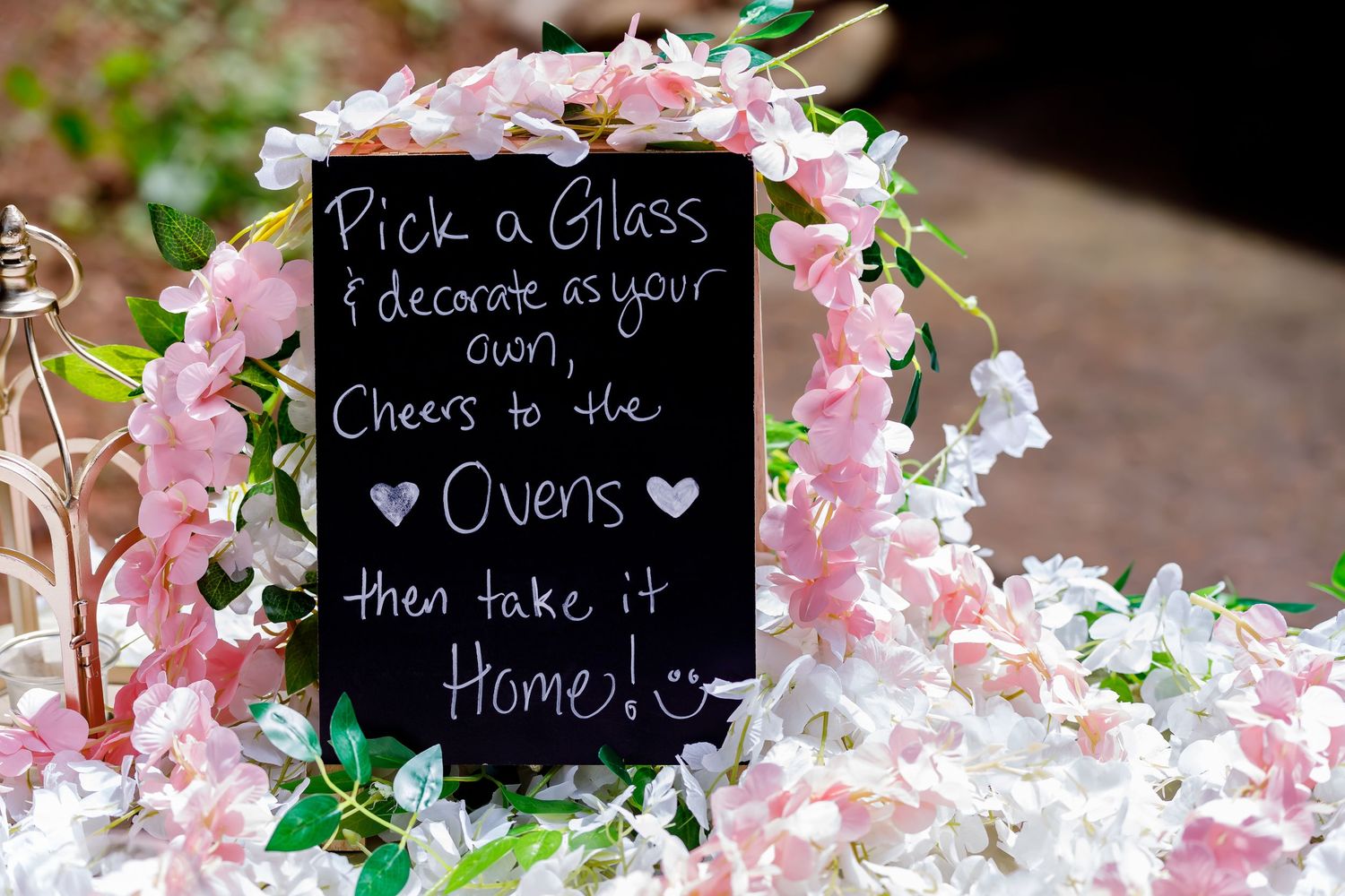 Wedding reception decor featuring chalkboard signs and pink floral arrangements.