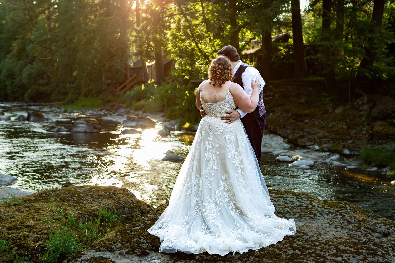 Wedding couple embraces by a scenic river during golden hour photography session.